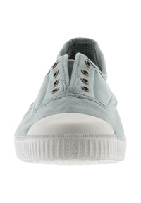 Baskets en toile bleu clair à enfiler, avec une semelle en caoutchouc blanc et un capuchon de pointe, comportant six œillets métalliques de chaque côté sans lacets.