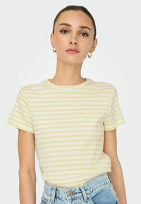 Stribet kortærmet t-shirt i lys gul og hvid, med ribbet tekstur og en klassisk rund halsudskæring. Bæres med højtaljede denimshorts.