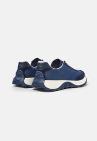 Sneakers in tessuto navy con superficie testurizzata e suole bianche, dotate di un tallone imbottito e suole spesse per una maggiore aderenza.
