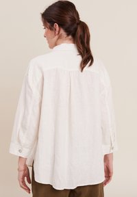 Witte linnen shirt met lange mouwen, een knoopsluiting bij de mouw en een subtiele plooi aan de achterkant, met een ontspannen pasvorm en een gebogen zoom.