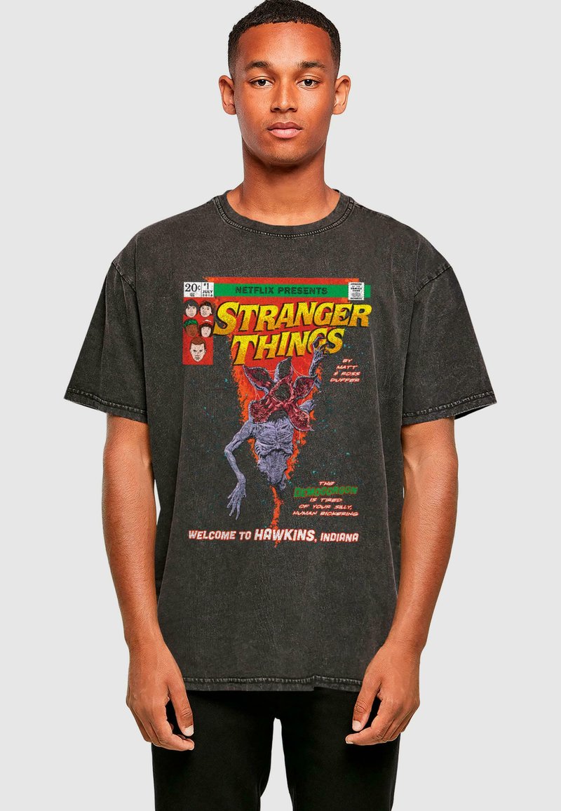 Black oversized t-shirt featuring a graphic print of a monster and text from "Stranger Things," with a distressed texture and round neckline.