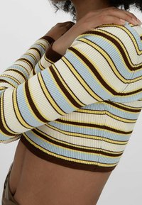 Prążkowany, krótki sweter z poziomymi paskami w jasnoniebieskim, kremowym, żółtym i brązowym kolorze. Dopasowany krój z długimi rękawami i przylegającym dołem.