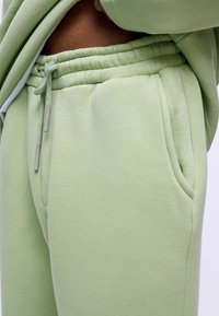 Lichtgroene trainingsbroek met een elastische tailleband en een trekkoord. Voorzien van zijzakken en een zachte, gladde textuur.