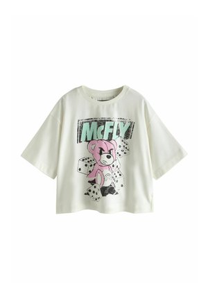 Hvid T-shirt med korte ærmer med tegneserie lyserød bjørn, sorte terninger og stor "McFLY" tekst i grøn og sort på forsiden.