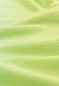 Tissu vert citron doux avec des plis légers et une texture lisse sous un éclairage diffus.