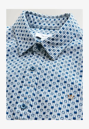 Camisa abotonada con un patrón geométrico azul y blanco, que presenta un cuello extendido, botones azules y un pequeño logo bordado cerca del dobladillo.