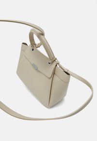 Borsa a mano in pelle beige con un design strutturato, doppi manici, tracolla regolabile, finiture in argento e superficie testurizzata.