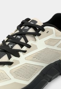 Baskets en mesh beige et noir avec des lacets noirs et des superpositions hexagonales, présentant l'inscription "PAL" sur l'étiquette de la langue.