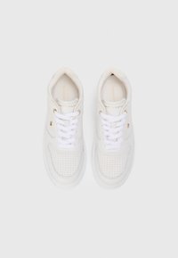 Une paire de baskets blanches Tommy Hilfiger avec une boîte à orteils perforée, des lacets blancs et un petit logo drapeau de chaque côté, vue d'en haut.