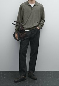 Olijfgroene gebreide polo coltrui, witte T-shirt, donkerdenim broek, donkerbruine tas met hengsels en zwarte veterschoenen.