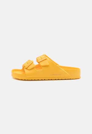 Sandale en caoutchouc jaune avec deux sangles à boucle réglables, semelle intérieure texturée et semelle extérieure striée pour une meilleure adhérence. Design simple et ouvert.