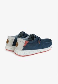Navy canvas shoes with a speckled white sole. Light gray accents on the heel and tongue, featuring orange eyelets and patterned lining.
