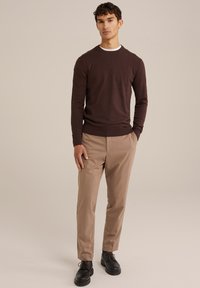 Suéter de cuello redondo marrón, pantalones de vestir beige, zapatos negros de cordones. Tela suave, diseño ajustado, patrón liso, fondo liso.