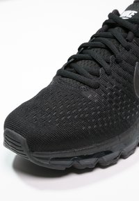 Scarpa da ginnastica nera con tomaia in maglia testurizzata, con punta rotonda, lacci neri e suola con ammortizzazione ad aria visibile.