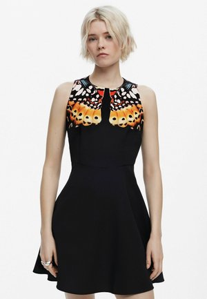 Ärmelloses schwarzes Kleid mit einem Schmetterlingsflügel-Druck in Orange und Weiß am Ausschnitt. Glockenrock-Design mit glatter Textur.