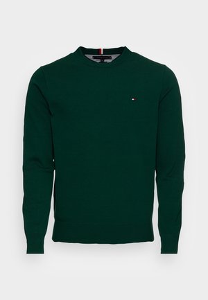 Maglione verde scuro a manica lunga con scollo rotondo, polsini e orlo a costine, con un piccolo logo rosso, bianco e blu sul petto.
