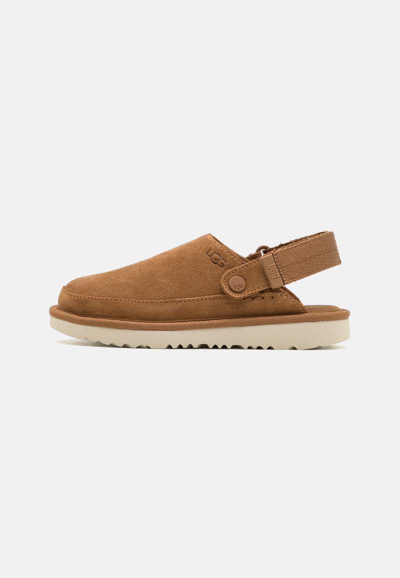 Bruna mockaskor med halkfri sula, slingback-design och en sidoknapp som accent. Texturerad ovandel med sömnad längs kanten.