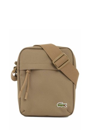 Lille firkantet tan crossbody taske med justerbar rem, front lynlåslomme og grønt krokodillelogo i nederste højre hjørne.