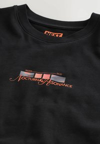Chemise noire avec le texte « Nocturnal Resonance » en orange sous un motif rectangulaire présentant des blocs de couleur dégradée et un petit texte « Neon Ritual » et « 26:07 ».