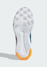 Suola di scarpa con grip bianco testurizzato, scanalature circolari nella sezione centrale e gomma arancione sul tallone, posizionata su uno sfondo semplice.