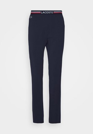 Marineblaue Hose mit taillierter Passform, elastischem Bund mit roten und weißen Streifen und einem dezenten Lacoste-Logo auf der Vorderseite.