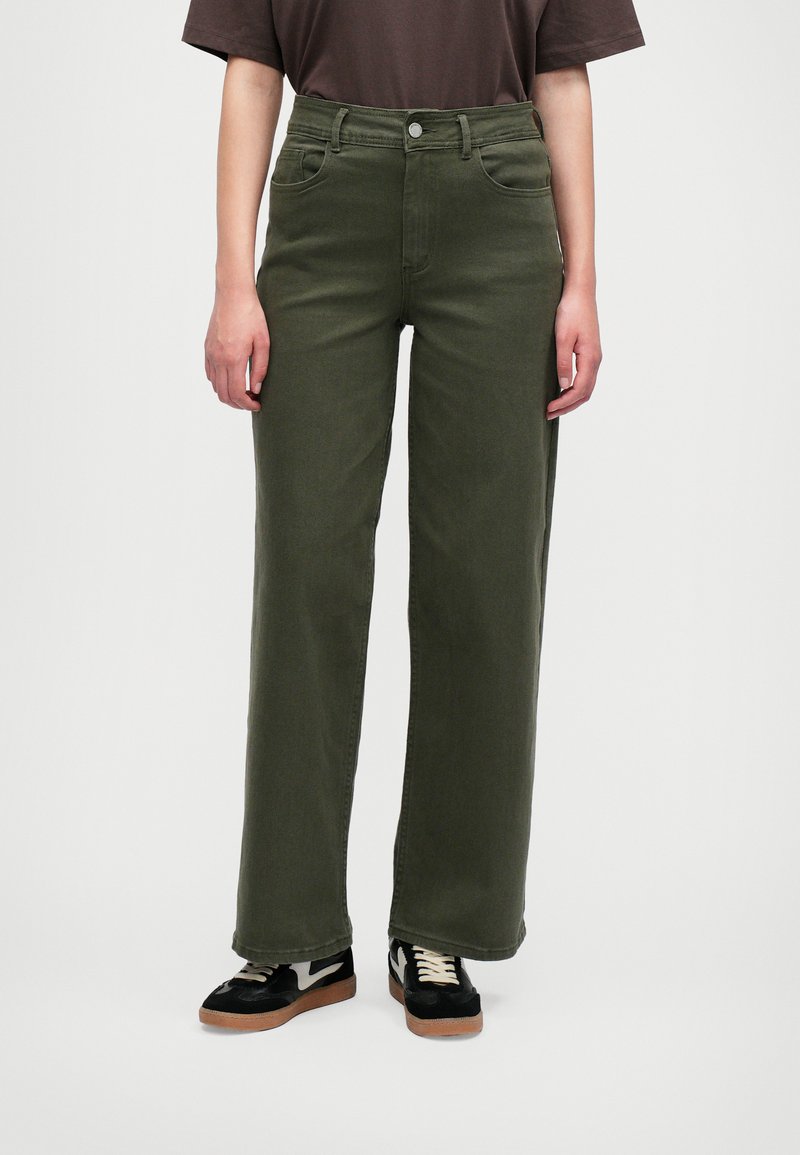 Olivově zelené kalhoty s širokými nohavicemi, vysokým pasem, pěti kapsami a jedním předním knoflíkem. V kombinaci s černými teniskami se bílým akcentem.