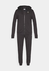 Sweat à capuche zippé noir avec cordon de serrage à la capuche, poignets et ourlet côtelés ; assorti d'un pantalon de survêtement avec chevilles élastiquées.