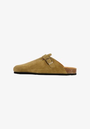 Zoccolo in suede marrone con forma curva, accentuato da una fibbia regolabile e suola in sughero-lattice, caratterizzato da un tacco leggermente rialzato e superficie testurizzata.