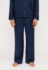 Navy striped pajama set in lightweight fabric, featuring a button-up jacket with two front pockets and matching loose-fitting pants.