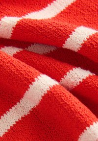 Rood gebreid stof met afwisselend witte strepen, die een zachte textuur en een iets losse weefstructuur toont.
