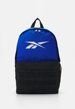 Mochila azul y negra hecha de un tejido duradero, con un logotipo blanco prominente, bolsillo lateral de malla y múltiples correas de tejido en la parte frontal.