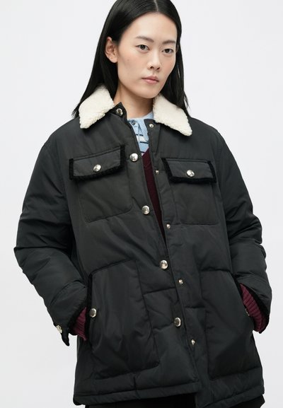 Sort polstret jakke med en hvid faux shearling krave, knaplukning og to brystlommer med dekorativ sort kant.