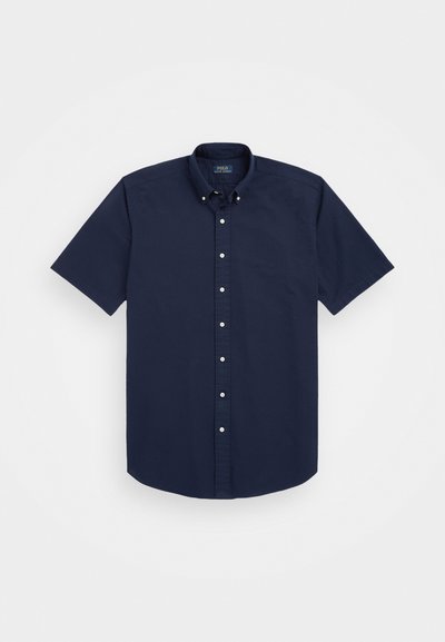 Chemise à manches courtes, boutonnée, en coton bleu marine. Elle présente un col classique, une patte de boutonnage à l'avant avec des boutons blancs et un motif texturé subtil.