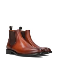 Bottines Chelsea en cuir marron avec des panneaux élastiques sur les côtés, des bouts ronds et des languettes de tirage. Texture lisse et semelles noires plates.