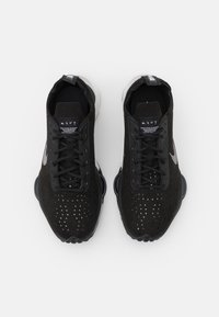 Paire de baskets noires Nike avec dessus perforés, logos swoosh blancs et lacets noirs vues de dessus sur fond blanc.