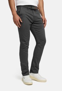 Pantaloni chino grigi a taglio slim in cotone, con tasche laterali e cintura texturizzata bianca e nera. Abbinati a sneakers bianche.