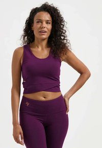 Lila kurzes Tanktop mit rundem Ausschnitt, kombiniert mit hoch taillierten lila Leggings. Beide Kleidungsstücke zeichnen sich durch eine glatte Textur und ein minimalistisches Design aus.