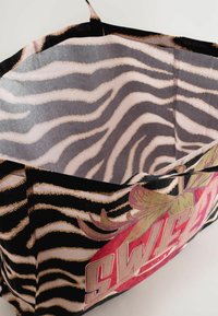 Stof tote tas med sorte og beige zebra striber og et r�ødt blomstermotiv med ordet "SWEET" på ydersiden.