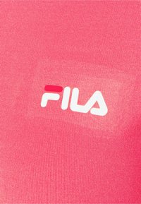 Červená texturovaná tkanina s viditelným jemným žebrováním. Bílé logo značky "FILA" vytištěné na očích, s červeným akcentem.