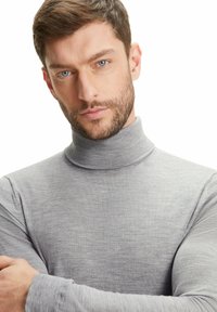 Maglione a collo alto grigio realizzato in morbido tessuto a costine. Presenta maniche lunghe e un collo alto. Texture liscia con cuciture minime.