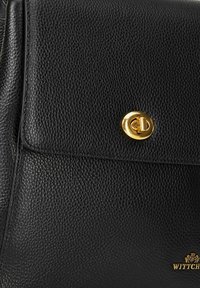Borsa a tracolla in pelle nera texture, caratterizzata da una chiusura circolare in tono dorato e logo impresso. Il design presenta linee pulite e accenti minimi.