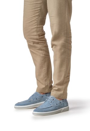 lichtblauwe suède schoenen met witte rubberen zolen en veteraccenten, gecombineerd met beige slim-fit broeken, met een gladde textuur.