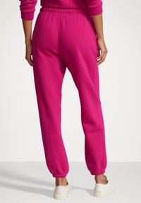 Fuchsiarosa joggers med elastisk midja, avsmalnande muddar och mjukt tyg. Designade för komfort och rörelsefrihet.