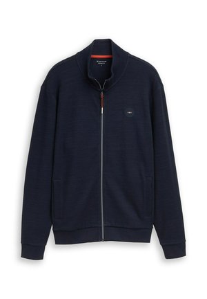 Giacca blu navy con cerniera completa, colletto alto, due tasche anteriori e piccolo logo circolare sul petto a sinistra.