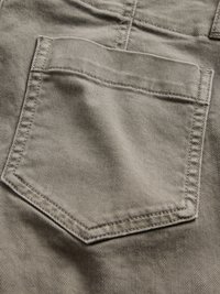 Tissu en denim beige clair avec une poche arrière rectangulaire dotée de coutures accentuées et d'une surface texturée.