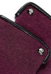 Lila Filzprodukt mit schwarzem Lederbesatz und Metallelementen, das ein Schädelmotiv aufweist. Die Textur ist weich und hat ein dichtes Erscheinungsbild.