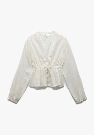 White, peplum blouse made of textured fabric. Features a deep V-neck, long sleeves, and a tie detail at the waist.