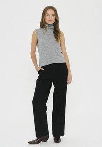 Top fără mâneci, gri, cu gât înalt, combinat cu pantaloni largi cu talie înaltă, negri, și cizme până la gleznă, burgundy, pe un fundal alb simplu.