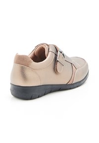 Scarpa in pelle beige con finitura testurizzata, dotata di una fascia in velcro, colletto imbottito e suola in gomma nera con battistrada sagomato.