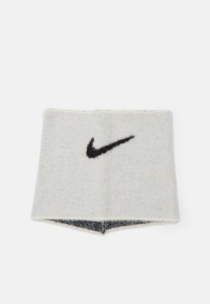 Un bandeau Nike en tissu tricoté blanc avec une texture pelucheuse. Il présente un logo swoosh noir brodé, avec un dessous gris.